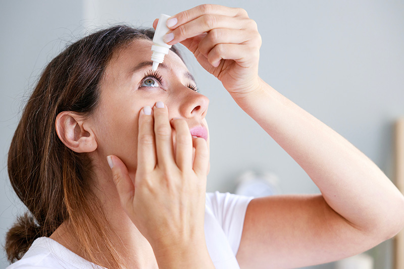 Woman putting eye drops in eye.